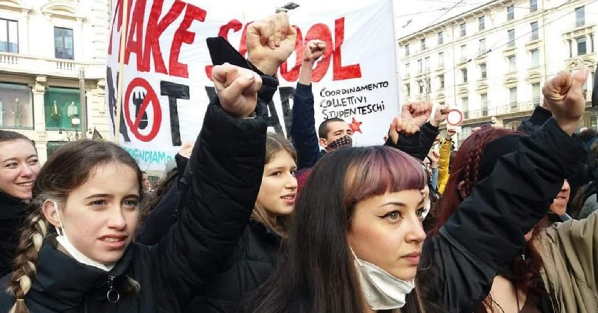 Due ragazze col pugno chiuso al cielo durante una manifestazione studentesca a Milano