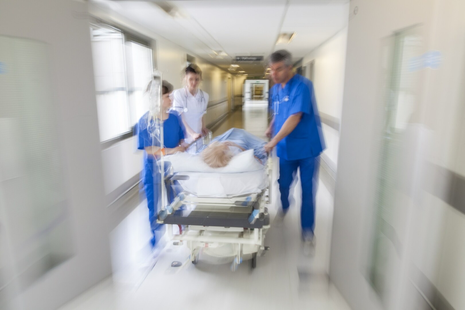 Una corsia di ospedale con infermieri che trasportano un paziente in barella